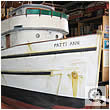 Close view of a tuna fishing boat hull and wheelhouse with name painted on the bow