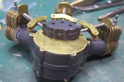 Close view of model components with enlarged holes in plastic and brass parts prepared for pin fasteners