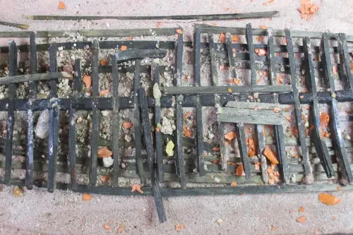 Top-down view of a scale model of the Kyrenia shipwreck, showing broken wooden hull ribs scattered across a sandy seabed with debris.