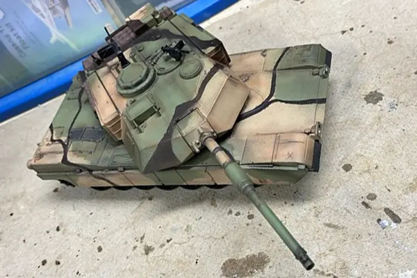 Close view of an M1 Abrams tank scale model with camouflage finish on a workshop surface