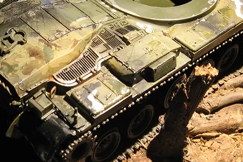 Close-up of an M60 Patton tank model hull during assembly, shown without the turret and exposing surface details and fittings.