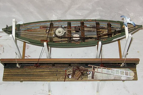 New Bedford whaleboat in a diorama, shown stowed as it would be aboard a whaleship, with partially painted inboard interior.